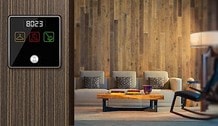 Simple Slave Economy Series small bell slave unit — compact black panel with red LED room number 8023 and DND/service icons mounted on wood-panel hotel room wall